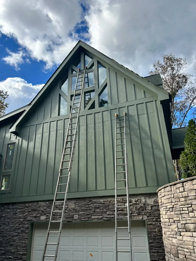 Painter working from ladders on a tall residential exterior